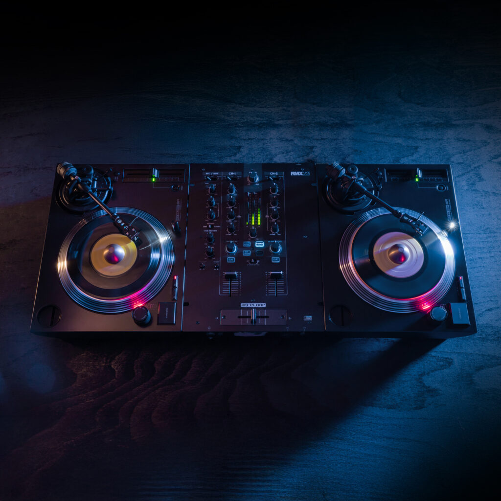 Dual Reloop RP-7 7-inch turntables with Reloop RMX-22i mixer in a professional DJ setup, illuminated with blue and red lighting