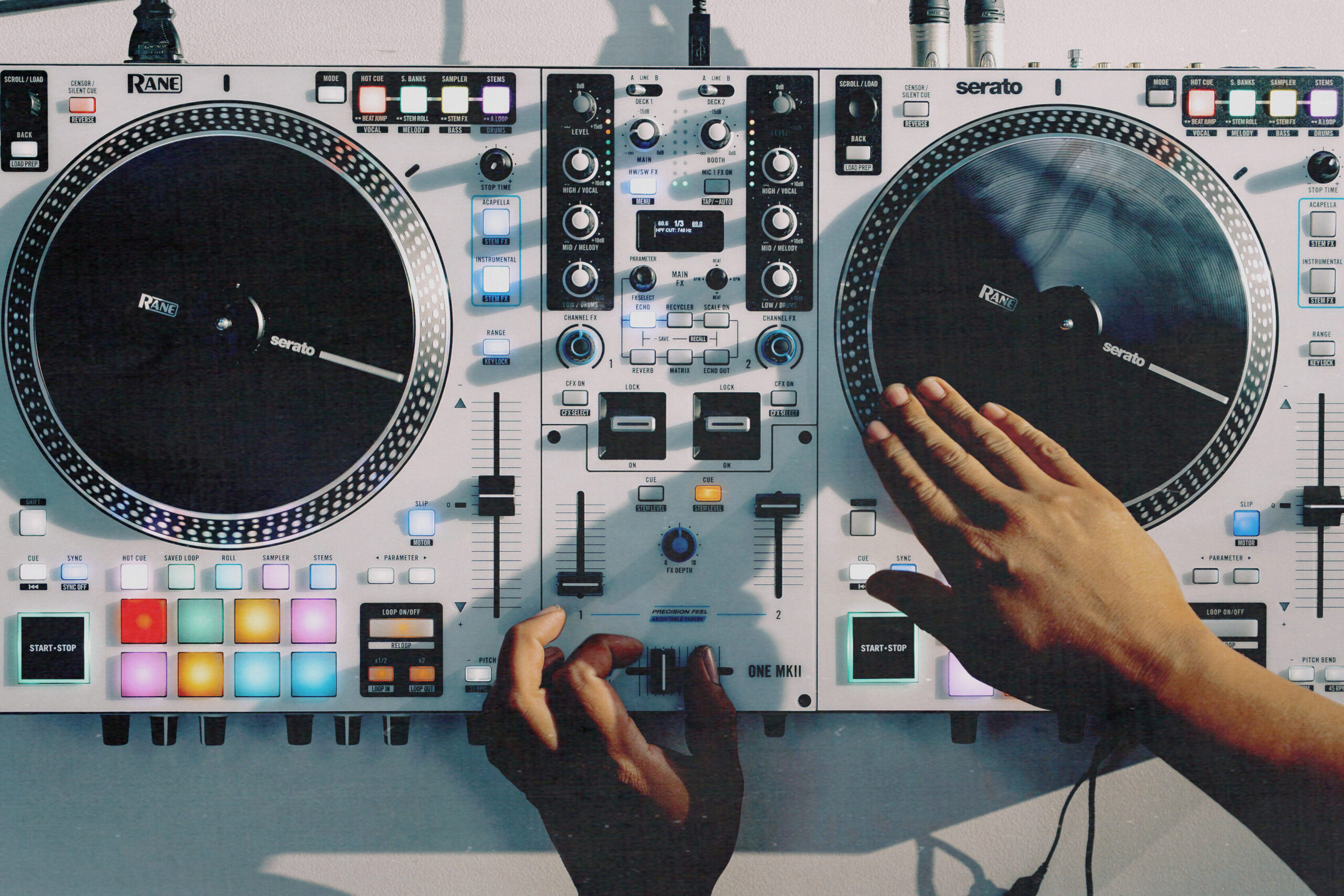 DJ using the RANE ONE MKII controller in a live setup, showcasing motorized platters, RGB performance pads, and active FX controls in a bright studio environment